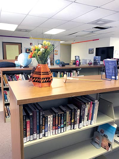 A bookshelf decorated with traditional weaving items atop it.